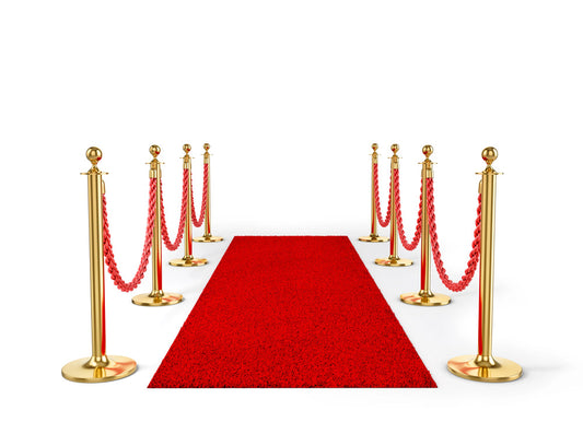 Red carpet leads between gold stanchions linked by red ropes against a white background, suggesting a formal entrance or ceremonial walkway.