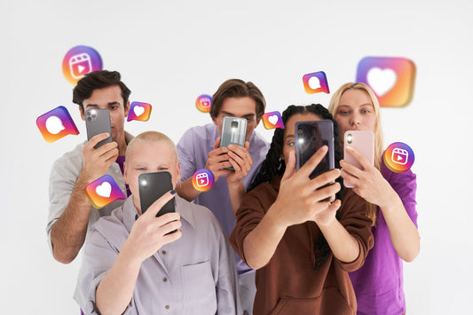 Group of five people taking selfies with smartphones in a plain studio, surrounded by floating social-media like and reel icons.
